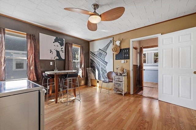 dining room featuring light wood finished floors, a ceiling fan, and crown molding