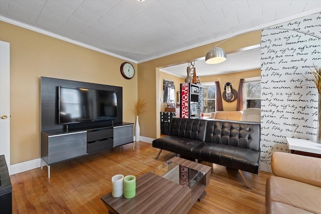 living area with baseboards, hardwood / wood-style flooring, and crown molding