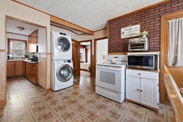 kitchen featuring stacked washer and clothes dryer, crown molding, light countertops, white electric range, and stainless steel microwave