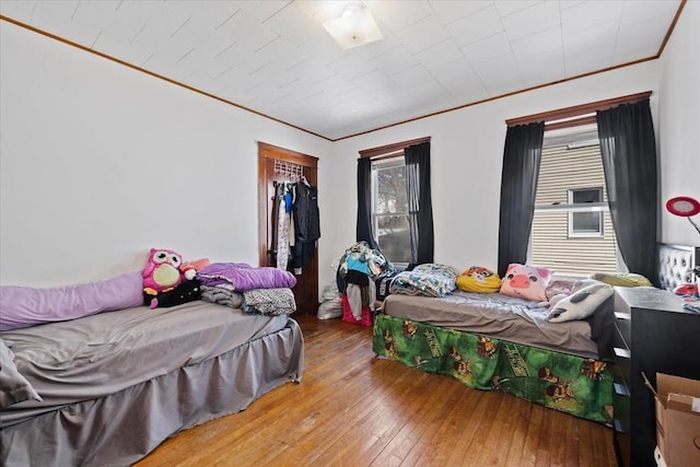 bedroom with ornamental molding, a closet, and wood-type flooring