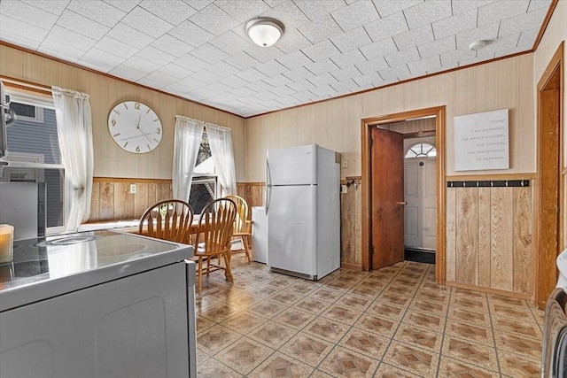 kitchen featuring wooden walls, range with electric stovetop, freestanding refrigerator, and crown molding