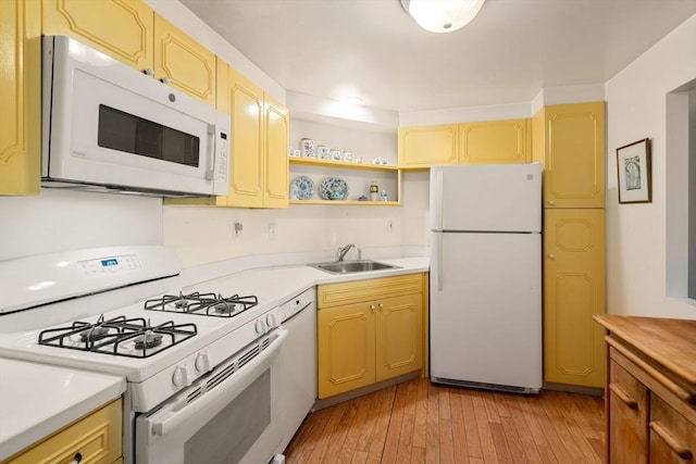 kitchen with white appliances, light wood finished floors, open shelves, a sink, and light countertops