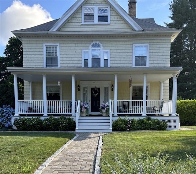 view of front of property featuring covered porch, a chimney, and a front lawn