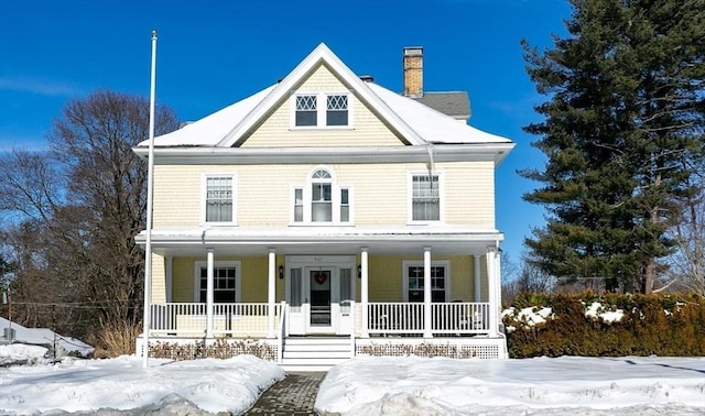 view of front facade with covered porch and a chimney