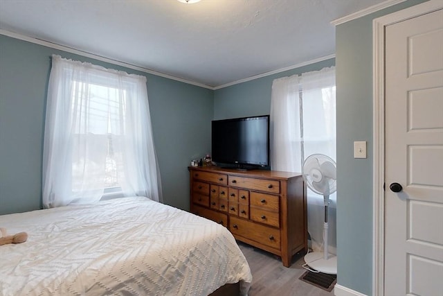 bedroom with ornamental molding and light hardwood / wood-style floors