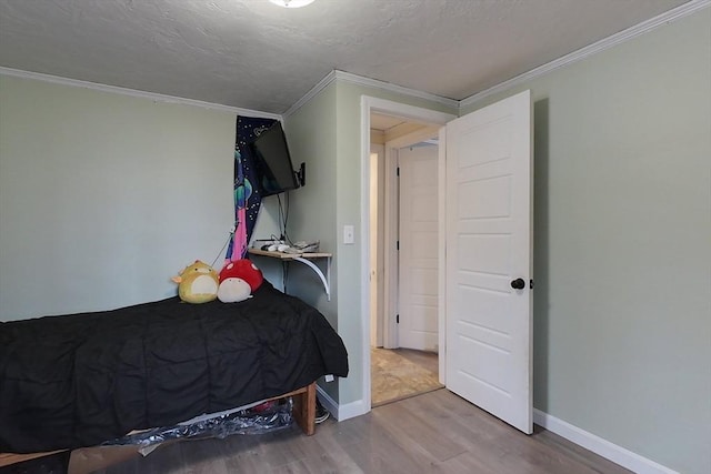 bedroom featuring crown molding, wood-type flooring, and a textured ceiling