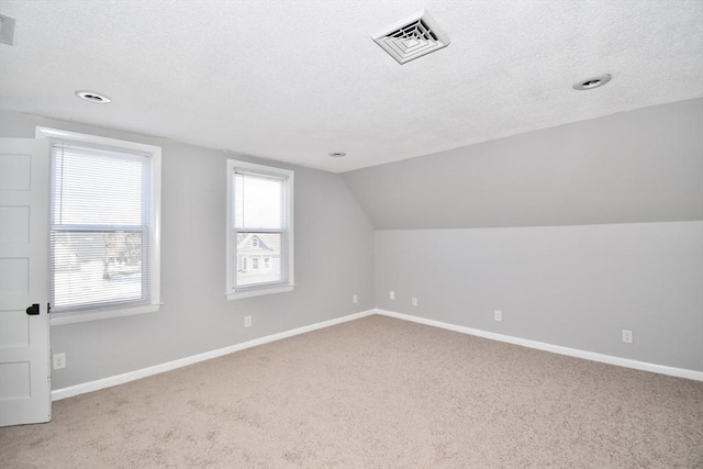 bonus room featuring lofted ceiling, visible vents, carpet flooring, a textured ceiling, and baseboards