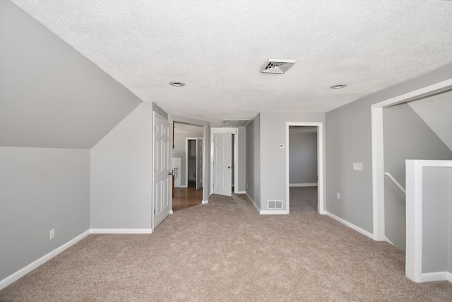 bonus room featuring light colored carpet, visible vents, and a textured ceiling