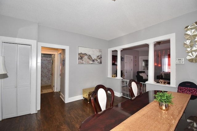 dining area featuring decorative columns, baseboards, and wood finished floors