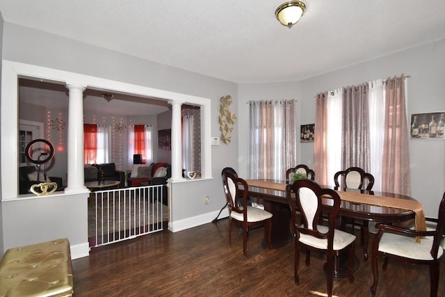 dining room with ornate columns, baseboards, and wood finished floors