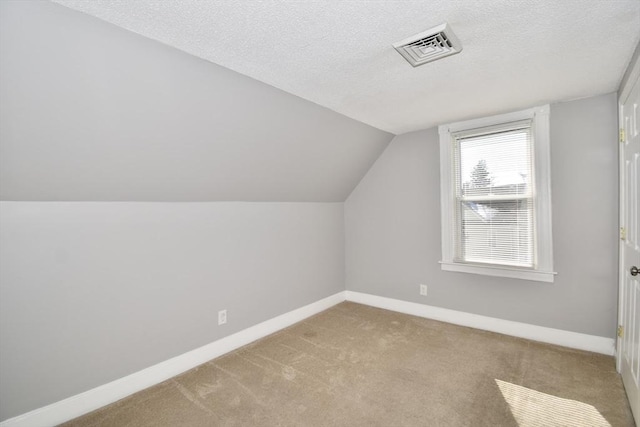 bonus room with a textured ceiling, lofted ceiling, carpet floors, visible vents, and baseboards