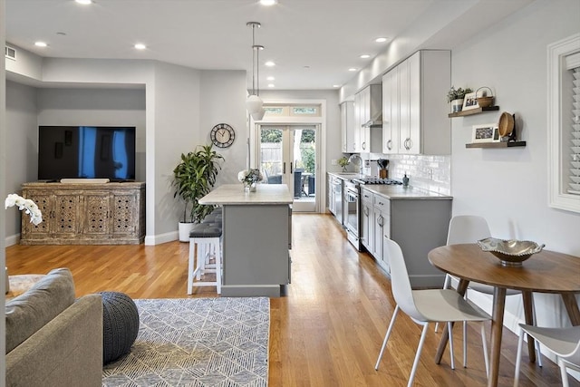 kitchen with tasteful backsplash, light countertops, french doors, and stainless steel range with gas stovetop