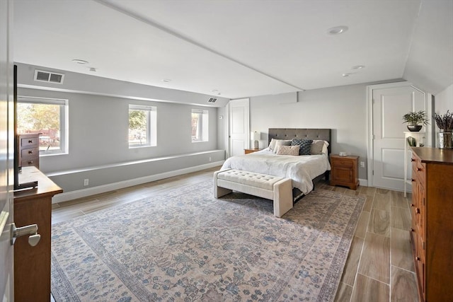 bedroom with wood tiled floor, visible vents, vaulted ceiling, and baseboards