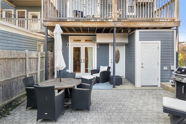 view of patio featuring outdoor dining area, a balcony, fence, a grill, and french doors