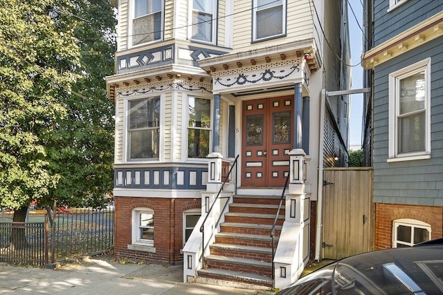 entrance to property featuring brick siding and fence