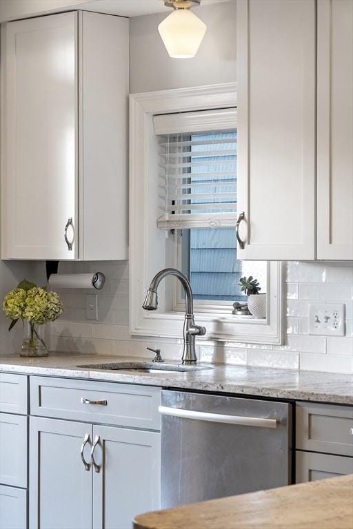 kitchen with tasteful backsplash, white cabinetry, a sink, and stainless steel dishwasher