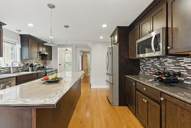 33 Walworth St, Worcester, MA 01602 - kitchen featuring stainless steel appliances, a kitchen island, light wood-style floors, decorative backsplash, and light stone countertops