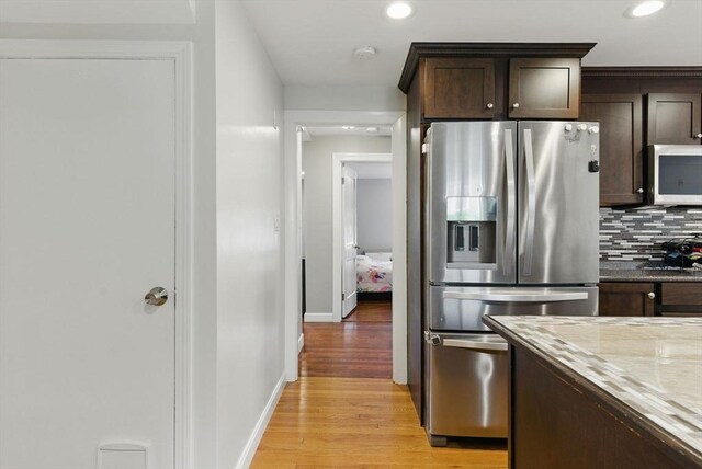 33 Walworth St, Worcester, MA 01602 - kitchen with appliances with stainless steel finishes, decorative backsplash, dark brown cabinetry, light wood-style flooring, and light stone counters