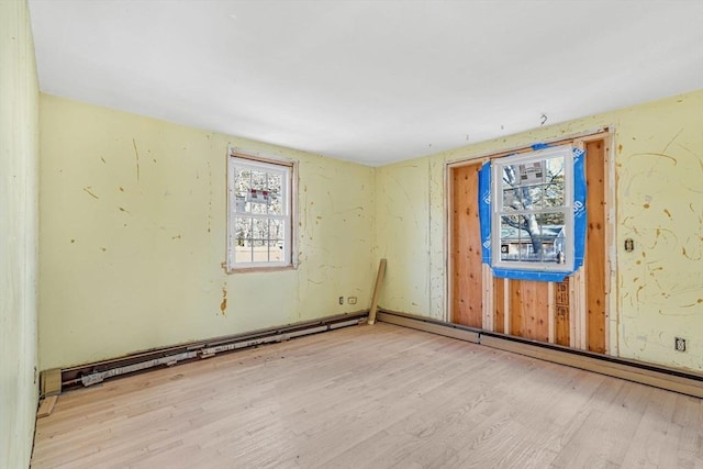 unfurnished room featuring baseboard heating and light wood-type flooring