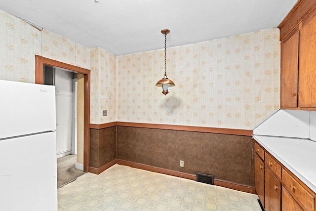 15 Rand St, Randolph, MA 02368 - kitchen featuring freestanding refrigerator, brown cabinetry, light countertops, wallpapered walls, and hanging light fixtures