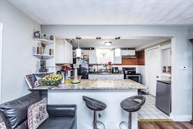 kitchen with tasteful backsplash, electric stove, decorative light fixtures, white cabinets, and fridge