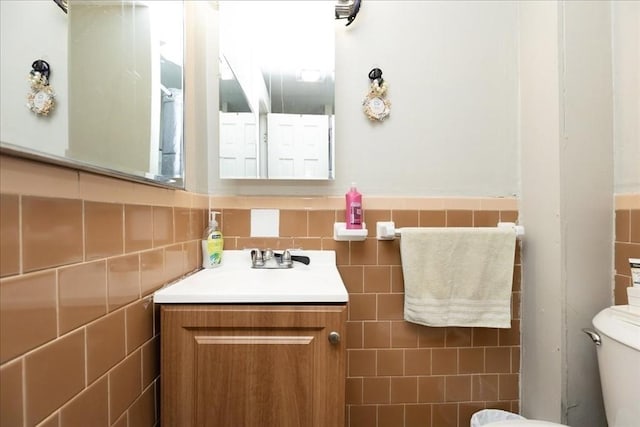 bathroom featuring vanity, tile walls, and toilet