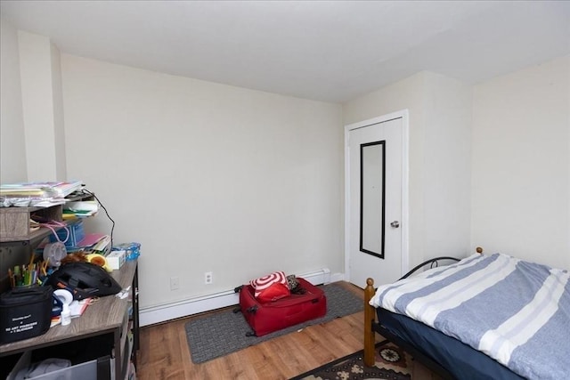 bedroom with dark hardwood / wood-style floors and a baseboard heating unit