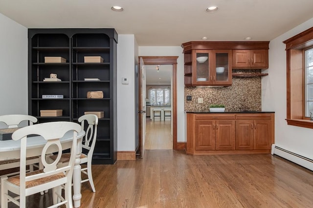 kitchen with a baseboard heating unit, wood-type flooring, and tasteful backsplash