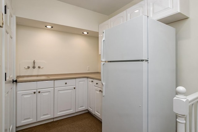 kitchen featuring white cabinets, white refrigerator, and sink