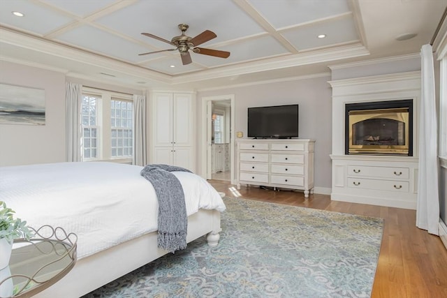 bedroom featuring coffered ceiling, ensuite bathroom, crown molding, light hardwood / wood-style flooring, and ceiling fan