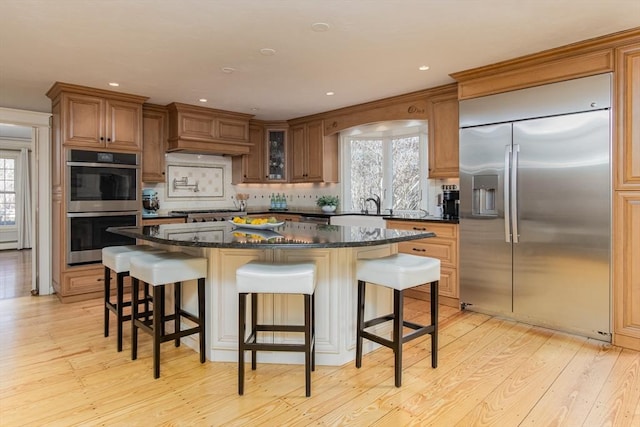 kitchen featuring dark stone countertops, decorative backsplash, a center island, and stainless steel appliances