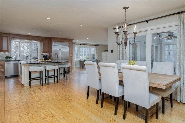 dining area with sink, light hardwood / wood-style floors, and a notable chandelier