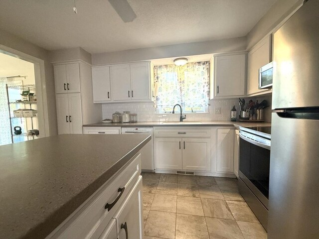 6 Gates St, Monson, MA 01057 - kitchen featuring stainless steel appliances, backsplash, white cabinetry, and dark countertops