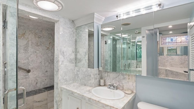 bathroom featuring marble finish floor, tile walls, toilet, a shower stall, and vanity