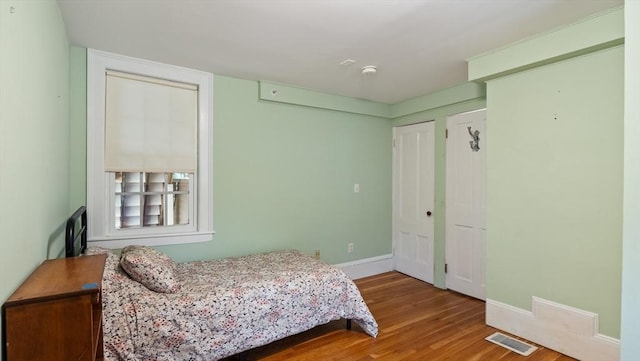 bedroom with visible vents, baseboards, and wood finished floors