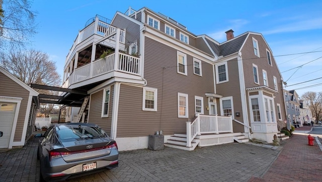 view of front of house with a balcony and a chimney