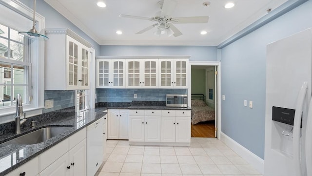 kitchen featuring white dishwasher, stainless steel microwave, backsplash, and a sink