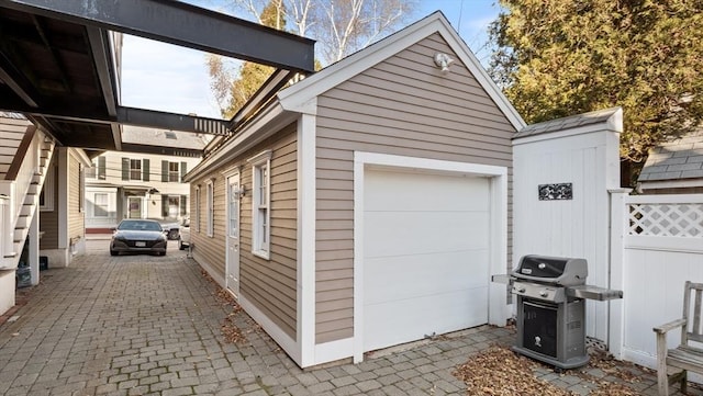 view of property exterior featuring a garage, fence, and an outbuilding