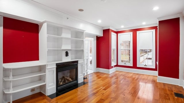 unfurnished living room featuring ornamental molding, a fireplace with flush hearth, light wood-style flooring, and baseboards