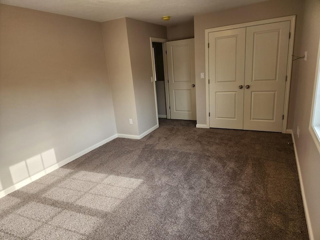 unfurnished bedroom featuring a closet and dark colored carpet