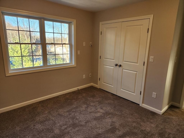 unfurnished bedroom with a closet and dark colored carpet