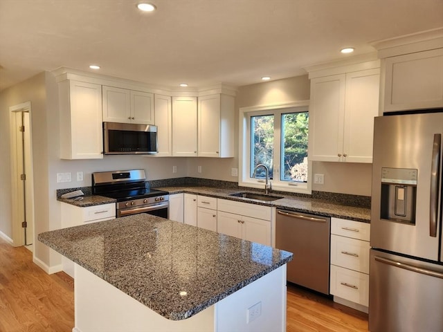 kitchen with white cabinets, appliances with stainless steel finishes, light hardwood / wood-style flooring, and sink