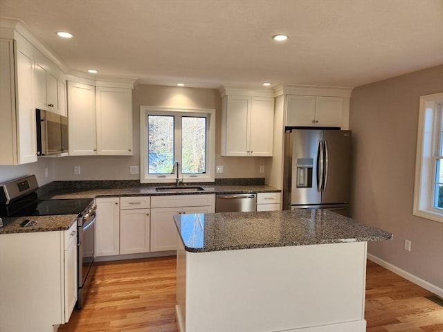 kitchen featuring sink, white cabinets, dark stone countertops, light hardwood / wood-style flooring, and appliances with stainless steel finishes