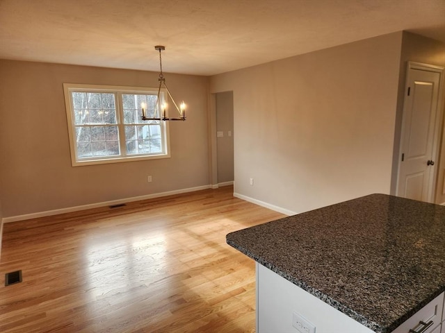 unfurnished dining area with a notable chandelier and light hardwood / wood-style floors