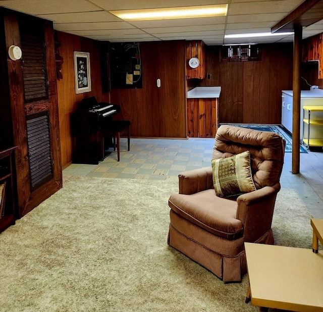 interior space with wooden walls, a drop ceiling, and light colored carpet