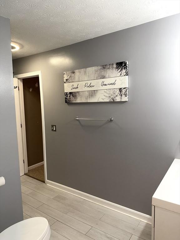 104 Orton St Unit 104, Worcester, MA 01604 - half bath featuring toilet, wood finished floors, a textured ceiling, vanity, and baseboards