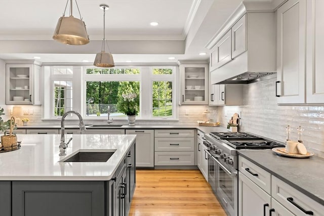 kitchen with glass insert cabinets, range with two ovens, a sink, and pendant lighting