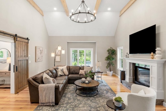 living area featuring light wood-style floors, a barn door, high vaulted ceiling, and beamed ceiling