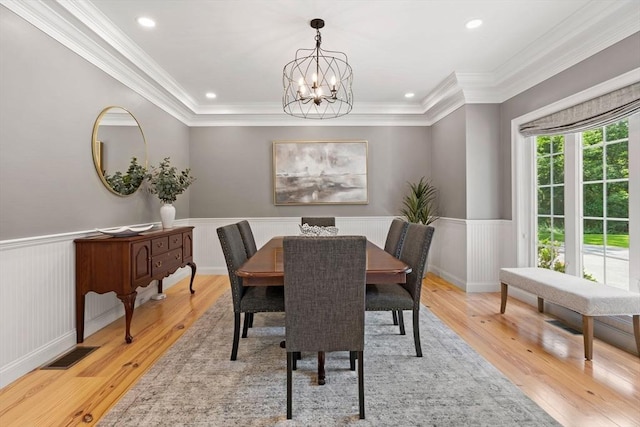 dining room with light wood-style flooring, visible vents, and wainscoting