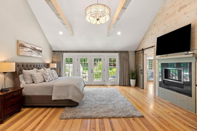 bedroom with access to exterior, multiple windows, light wood-style flooring, and a barn door